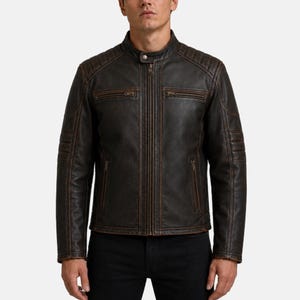 May include: A dark brown leather jacket featuring a stand-up collar with a snap button, a full-length central zipper, and two horizontal zippered chest pockets. The shoulders and sleeves include quilted panel detailing with visible brown stitching.