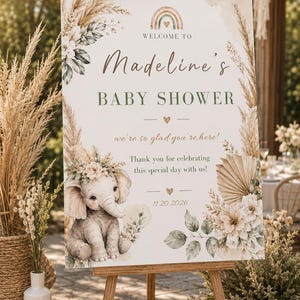 May include: A rectangular welcome sign for a baby shower featuring a watercolor illustration of a baby elephant with a floral crown, pampas grass, and a rainbow. The text reads: Welcome to Madeline's Baby Shower, we're so glad you're here, and 11.20.2026.