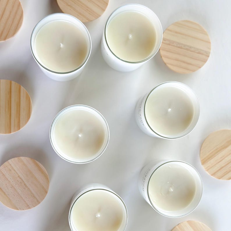 May include: A flat lay of nine white candles with wooden lids. The candles are arranged in a circle with the lids in between each candle.