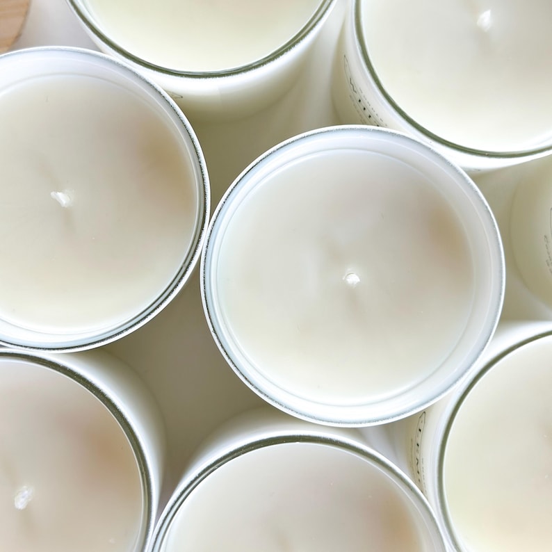 May include: A close-up view of several white candles with a clear glass container. The candles are arranged in a circular pattern.
