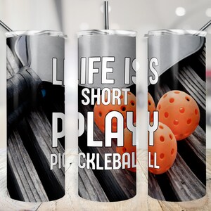K&ouml;nnte beinhalten: Ein Edelstahlbecher mit Holzmaserung im Hintergrund und orangefarbenen Pickleball-B&auml;llen. Auf dem Becher steht der Text "Life is short, play pickleball".