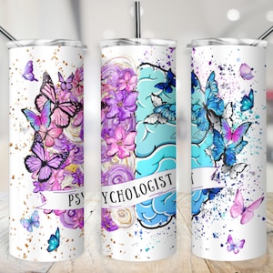 Puede incluir: Tres vasos de acero inoxidable con fondo blanco y un diseño de un cerebro con mariposas. Los vasos tienen el texto "Psicólogo" en ellos.