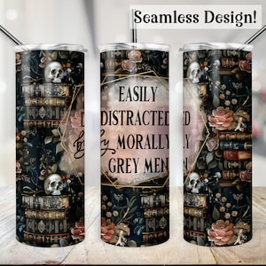 Pode incluir: Um copo de design sem costura com um padrão escuro de flores e livros, uma caveira e o texto "Easily Distracted by Morally Grey Men". O copo inclui uma palhinha prateada e uma moldura geométrica dourada.