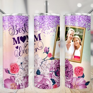 Pu&ograve; includere: Un bicchiere con glitter viola e rosa con un design floreale e il testo "Best Mom Ever". Una foto di una madre e una figlia &egrave; in una cornice dorata sul bicchiere.