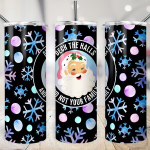 May include: A black and white tumbler with a watercolor snowflake and polka dot pattern. The tumbler has a white circle with the text "Deck the Halls and Not Your Family". A cartoon Santa Claus is in the circle.
