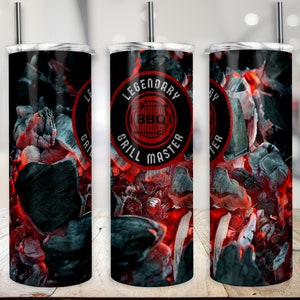 Könnte beinhalten: Drei Edelstahlbecher mit schwarzem Hintergrund und einem rot-weiß-schwarzen Design aus glühenden Kohlen. Der mittlere Becher hat einen schwarzen Kreis mit dem Text "Legendary Grill Master" und einen roten Kreis mit dem Text "BBQ" darin.