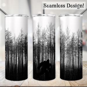 May include: A black and white stainless steel tumbler featuring a design of a silhouette of a creature walking through a forest of bare trees. The tumbler is seamless and has a straw.