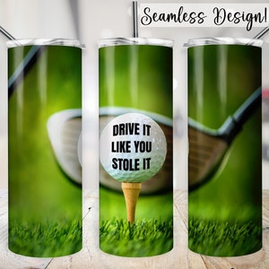 Puede incluir: Una bola de golf blanca con el texto "DRIVE IT LIKE YOU STOLE IT" en ella, sentada en un tee en un campo de golf verde. Un palo de golf está en el fondo.
