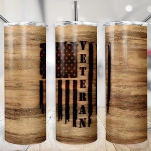 Puede incluir: Un juego de tres vasos de acero inoxidable con un patrón de veta de madera. El vaso del centro presenta una bandera estadounidense desgastada con la palabra "Veteran" escrita verticalmente a un lado.