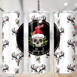 May include: White stainless steel tumbler with a black circle design featuring a skull wearing a Santa hat and the text "jolly af". The background is a white pattern of skulls with antlers and Christmas lights.