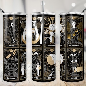 May include: Three black and gold stainless steel tumblers with images of tarot cards. The cards are Death, The High Priestess, The Sun, The Temperance, The Tower, The Devil, The Moon, and The Fool.
