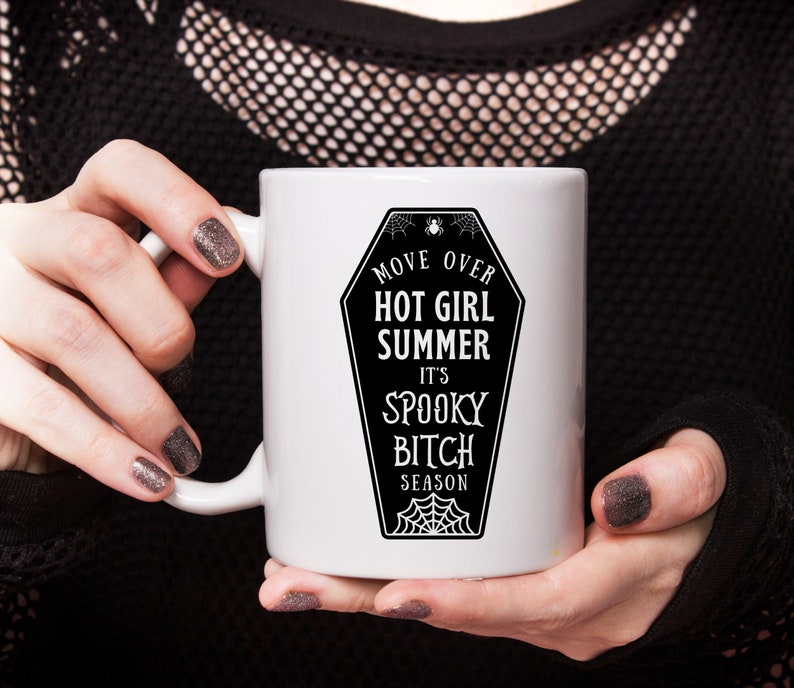 May include: White ceramic mug with a black and white graphic of a coffin with the text "Move Over Hot Girl Summer It's Spooky Bitch Season".