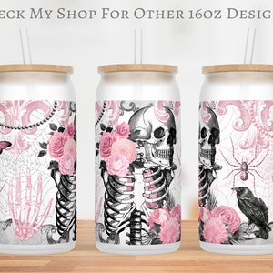 May include: Three 16oz stainless steel tumblers with a pink and black gothic design. The design features a skull, skeleton, roses, spiderwebs, and a spider. The tumblers have a wooden lid and a straw.
