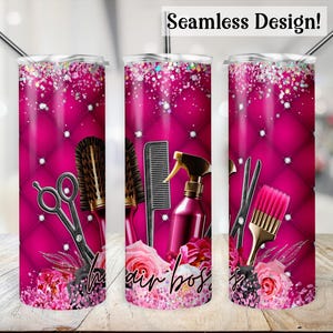 May include: Pink and black tumbler with a seamless design featuring hairdressing tools, including scissors, combs, a hairbrush, and a spray bottle. The tumbler has a pink background with a quilted pattern and a floral design at the bottom. The text "Hair Boss" is visible on the tumbler.