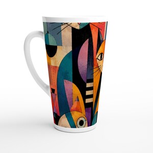 May include: A tall white ceramic mug featuring a colorful abstract graphic print of stylized cats. The design incorporates geometric shapes and bold blocks of orange, teal, black, purple, and yellow, creating a layered composition of feline forms.