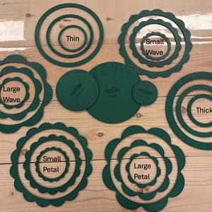 May include: A collection of dark green circular pottery cutters in various styles including thin, thick, small wave, large wave, small petal, and large petal designs, along with three solid circular discs featuring the text Pottery on the surface.