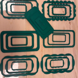 May include: A collection of dark green rectangular pottery cutters in various sizes, featuring both smooth and scalloped edges. One solid rectangular tool is included, clearly embossed with the text POTTERY and a logo, arranged in a set.