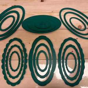 Könnte beinhalten: Ein Set aus dunkelgrünen, ovalen Töpfer-Ausstechformen aus Kunststoff in verschiedenen Größen. Die Sammlung umfasst ovale Rahmen mit glatten Kanten und ovale Rahmen mit gewelltem Rand, wobei das Wort POTTERY auf dem zentralen Teil steht.