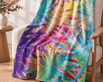 May include: A soft throw blanket featuring a vibrant, abstract watercolor print of palm leaves in shades of bright turquoise, sunny yellow, deep magenta, and royal purple, creating a colorful and layered botanical pattern across the fabric.