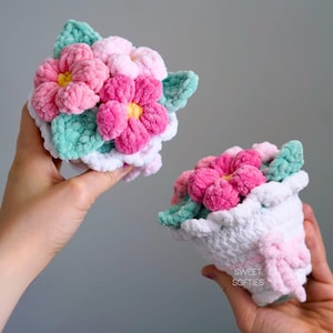Puede incluir: Dos ramos de flores de ganchillo, uno en rosa y blanco y el otro en rosa, verde y blanco. Los ramos se sostienen en manos y presentan una textura suave y esponjosa.