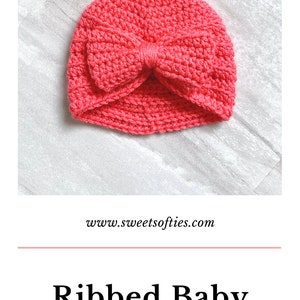May include: A pink crocheted baby turban with a bow on top. The turban is on a white textured surface. The text "www.sweetsofties.com" is below the turban. The text "Ribbed Baby Turban" is below the website address. The text "FREE PATTERN & VIDEO TUTORIAL" is below the turban name.