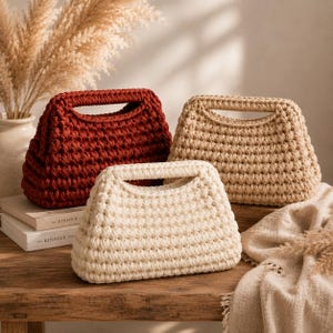 Puede incluir: Tres bolsos estructurados hechos de hilo grueso en colores sólidos. Un bolso es de color rojo oscuro, otro beige y otro blanco roto. Cada bolso presenta una forma rectangular con una abertura de asa ancha integrada en la parte superior y textura.