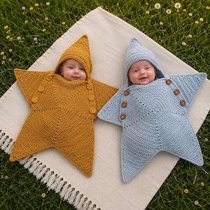 May include: Two star-shaped crochet swaddle blankets with pointed hoods, one in mustard yellow and one in light blue. Each swaddle features three brown buttons on both sides to secure the garment around the infant, creating a cozy star silhouette.