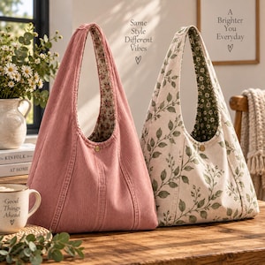 May include: Two hobo bags with a single shoulder strap and a central snap button closure. One bag is made of solid dusty pink corduroy with a floral interior lining. The other bag is made of cream fabric with a green leaf print and a floral lining.