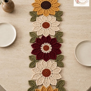 May include: A long, rectangular crochet table runner featuring a repeating pattern of large, multi-petalled flowers in yellow, cream, and deep burgundy, accented by small green leaves. The text BloomRunner Crochet is visible in the top corner.