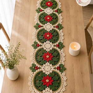 May include: A long, rectangular crochet table runner featuring a repeating pattern of red poinsettia flowers with gold centers, surrounded by dark green leaves and holly berries, all bordered by an intricate cream-colored lace edge.