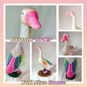 May include: A decorative goose figurine covered in iridescent crystals, featuring a bright pink beak and a rainbow-colored wing pattern. The text Custom Order and Full Size Goose is displayed. The goose stands on a green base.