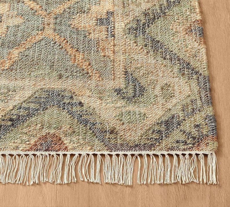Full overhead perspective of a muted sage green and terracotta geometric hand woven flat weave jute rug, a sustainable Naturteppich offering a clean botanical foundation perfect for replacing a massive area rug 14x14 or a generic 10x16 livingroom rug setup.