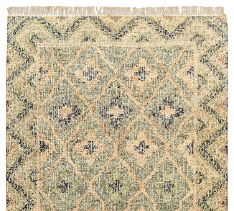 Close-up of the dense flatweave texture showcasing the peachy-tan accents and off-white fringe, an authentic Tapis en jute that is far superior to a lightweight tuft rug, an artificial shining rug, or poorly made hadncrafted rugs.