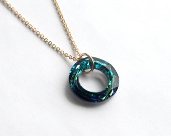 Peut inclure: Un collier en chaîne dorée avec un pendentif en cristal iridescent bleu et turquoise en forme de cercle.