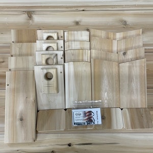 May include: A set of unfinished wooden birdhouse kits. The kit includes all the pieces needed to build a birdhouse, including the base, sides, roof, and entrance hole. The kit also includes a small bag of wood screws. The wood is a light brown color.