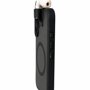 May include: A matte black smartphone case featuring a built-in circular magnetic charging ring on the back and an integrated holder at the top edge that secures a single white wireless earbud with a silicone tip in a vertical position.