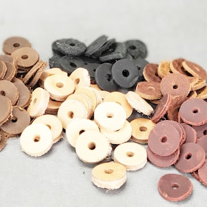 Pode incluir: Conjunto de anéis de couro em cores marrom, bege, preto e bordô. Os anéis estão empilhados em uma pilha sobre uma superfície cinza.