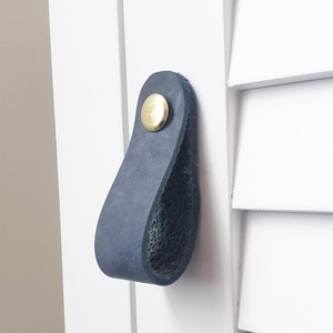 May include: A dark blue leather cabinet pull with a brass knob.