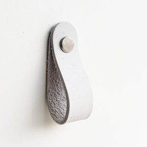 May include: White leather cabinet pull with a silver metal screw.