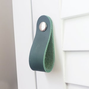 May include: A teal green leather cabinet pull with a silver knob.