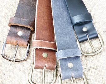 May include: Four leather belts with different colors and finishes, including brown, tan, gray, and black, with silver and brass buckles.