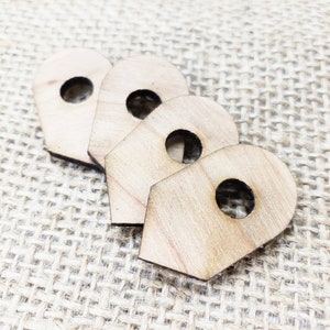 Puede incluir: Cuatro formas de madera sin terminar en forma de alfiler o marcador de mapa. Las formas están dispuestas en una fila, con la forma más grande en la parte inferior y la forma más pequeña en la parte superior. Las formas tienen un agujero en el centro.