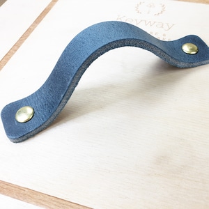 May include: A dark blue leather handle with gold metal accents. The handle is curved and has a simple design.