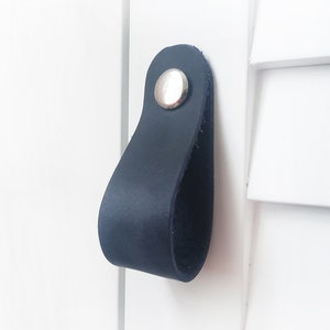 May include: Black leather cabinet pull with a silver metal knob.