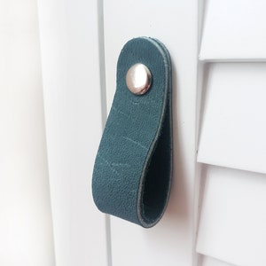 May include: Teal leather cabinet pull with a silver metal knob.