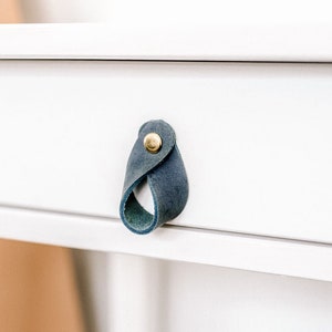 May include: White drawer with a blue leather pull handle and a gold knob.