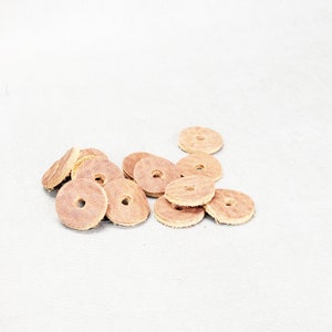 May include: A pile of brown leather round discs with a hole in the center. The discs are arranged in a random pattern on a white surface.