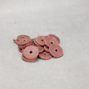 May include: A pile of brown leather washers, stacked and overlapping. The washers are round with a hole in the center.