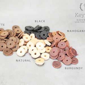 May include: Assortment of leather rings in various colors, including black, latte, natural, mahogany, and burgundy. The rings are arranged in a semi-circle on a gray surface. Keyway Hardware & Leatherworks is printed at the top of the image.