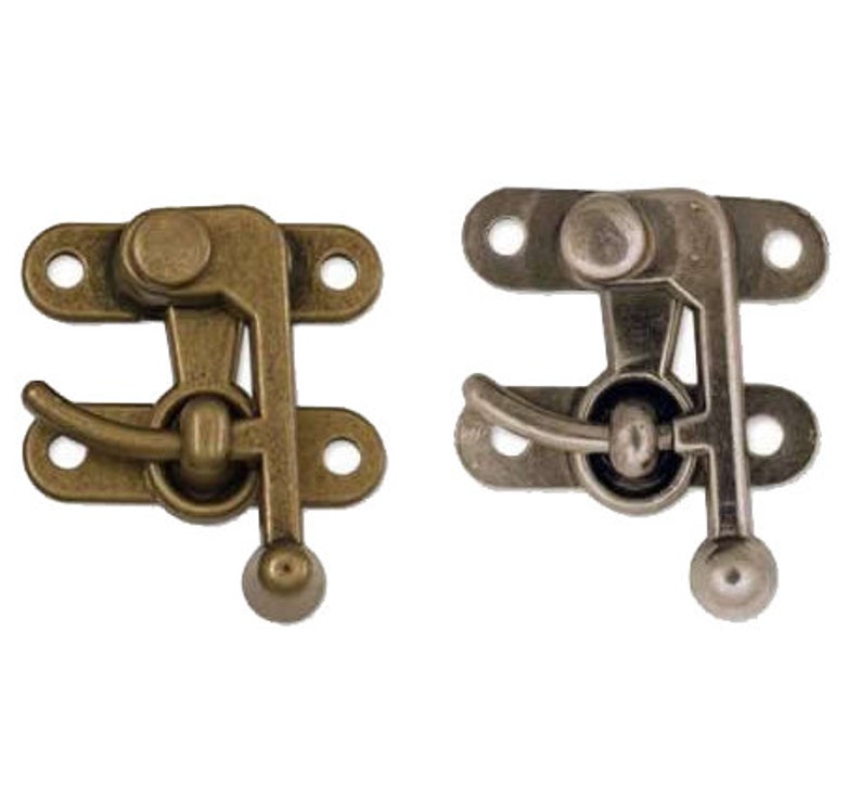 Pode incluir: Dois fechos de porta de arm&aacute;rio de estilo antigo. Um &eacute; de cor lat&atilde;o e o outro &eacute; de cor prata. Ambos t&ecirc;m uma pega de alavanca e um bot&atilde;o redondo.